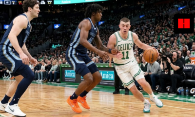 Action shot of a Boston Celtics player in a white home jersey dribbling past a Memphis Grizzlies defender in a blue away jersey at TD Garden.