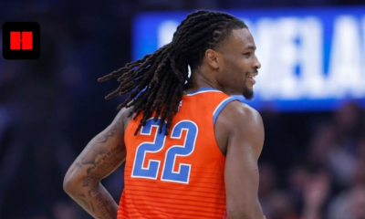 Oklahoma City Thunder guard Cason Wallace (number 22) smiling on court during an NBA game, wearing the orange Statement Edition jersey with his signature long dreadlocks in motion.
