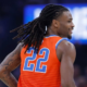 Oklahoma City Thunder guard Cason Wallace (number 22) smiling on court during an NBA game, wearing the orange Statement Edition jersey with his signature long dreadlocks in motion.