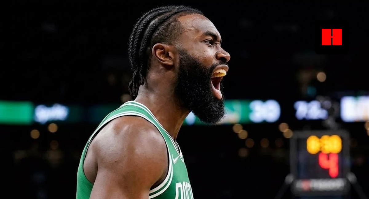 Jaylen Brown of the Boston Celtics shouting in celebration during a game, wearing a green jersey with white braided hair, side profile view in a dark arena.
