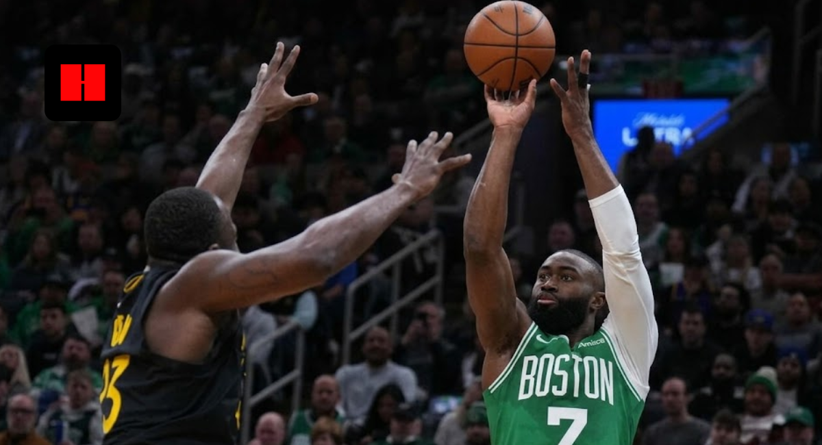 Boston Celtics' Jaylen Brown (7) shooting a high-arcing jump shot over a contesting Draymond Green (23) of the Golden State Warriors during an NBA game at TD Garden.