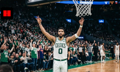 Jayson Tatum of the Boston Celtics wearing a white #0 jersey, raising his arms in celebration on the basketball court during a home game at TD Garden.