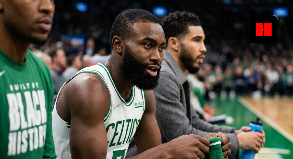 Jayson Tatum in street clothes sitting next to Jaylen Brown in a Celtics jersey on the team bench during a game.