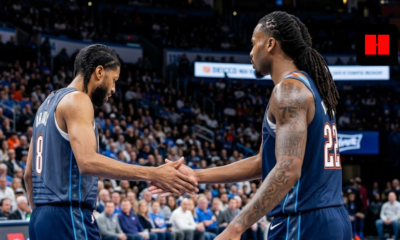 Two OKC Thunder basketball players with braids and tattoos shaking hands during a game from a side profile angle.