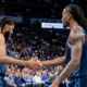 Two OKC Thunder basketball players with braids and tattoos shaking hands during a game from a side profile angle.