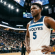 Anthony Edwards of the Minnesota Timberwolves standing on the court in a white Association Edition jersey, looking focused during a game.