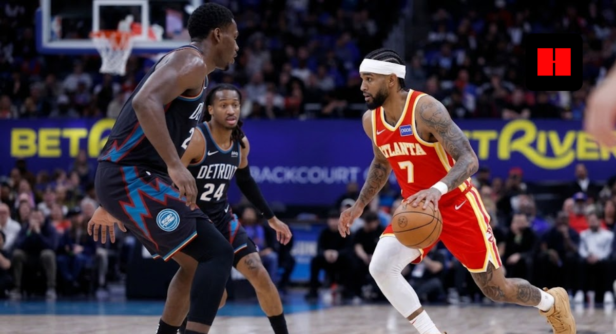 Atlanta Hawks player in red jersey number 7 dribbling the ball against a Detroit Pistons defender in a black jersey during an NBA game.