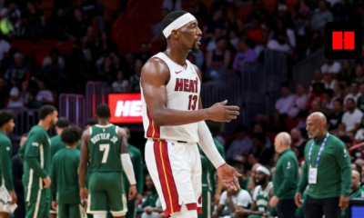 Miami Heat center Bam Adebayo wearing a white jersey and headband, gesturing on the basketball court during an NBA game.