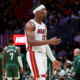 Miami Heat center Bam Adebayo wearing a white jersey and headband, gesturing on the basketball court during an NBA game.