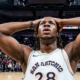 A low-angle shot of San Antonio Spurs player Charles Bassey (number 28) with his hands on his head in a crowded basketball arena.