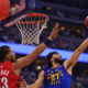 Denver Nuggets player attempting a right-handed layup while Toronto Raptors defender contests near the basket during an NBA game