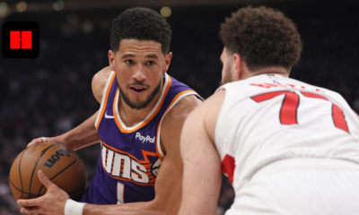 Devin Booker of the Phoenix Suns drives past a Toronto Raptors defender during an NBA game, showcasing ball control and offensive pressure in UHD action shot.