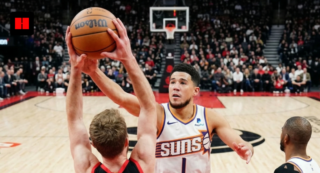 Phoenix Suns guard Devin Booker defending a shot by Toronto Raptors center Domantas Sabonis during an NBA game.