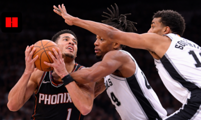 Devin Booker drives to the basket against double-team defense by San Antonio Spurs players during NBA game action.