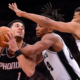 Devin Booker drives to the basket against double-team defense by San Antonio Spurs players during NBA game action.