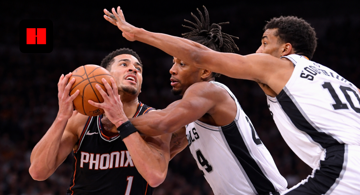 Devin Booker drives to the basket against double-team defense by San Antonio Spurs players during NBA game action.