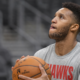 Former NBA player and Celtics coach Evan Turner practicing a jump shot in an Atlanta Hawks long-sleeve shirt during a pre-game warmup.