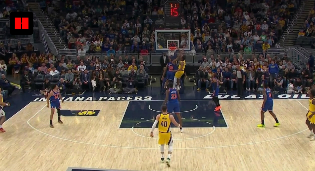 A high-angle wide shot of an Indiana Pacers basketball game at Gainbridge Fieldhouse, showing players in yellow and blue uniforms during a play near the basket.