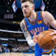 Isaiah Hartenstein of the Oklahoma City Thunder handles the ball during a live game, focused in the half-court offense with defenders closing in and crowd in the background
