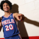 Jared McCain in Philadelphia 76ers jersey spins basketball on finger during media day photo shoot