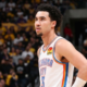 A close-up portrait photograph of Oklahoma City Thunder player Jared Mccain looking left during an NBA game, with his hand on his hip and a blurred crowd wearing yellow shirts in the background.