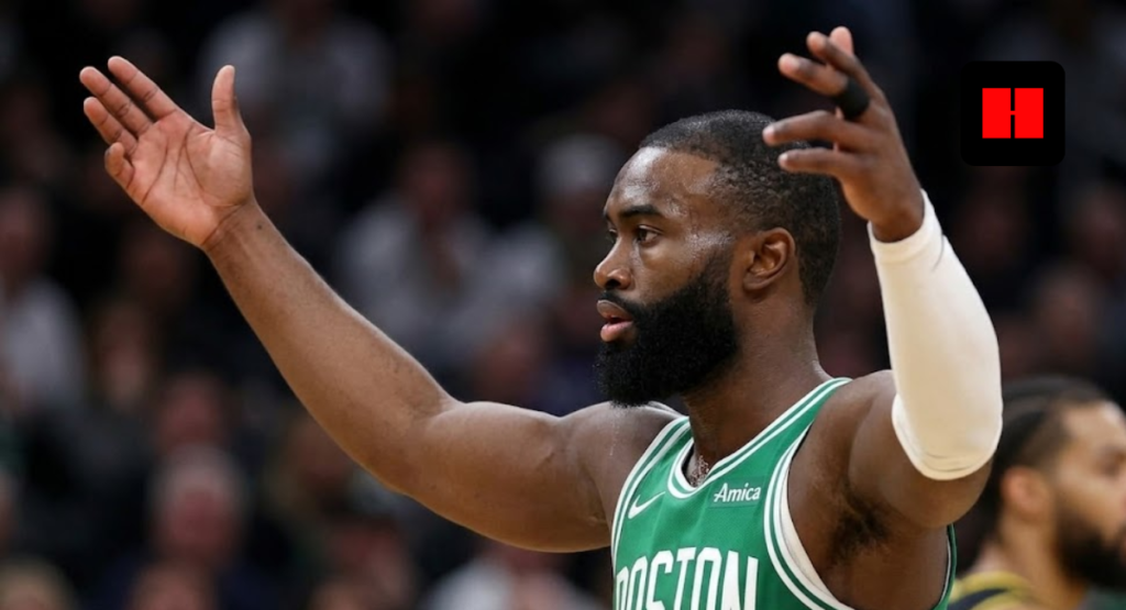 Jaylen Brown of the Boston Celtics wearing a green jersey and white shooting sleeve, gesturing with arms raised during a basketball game.