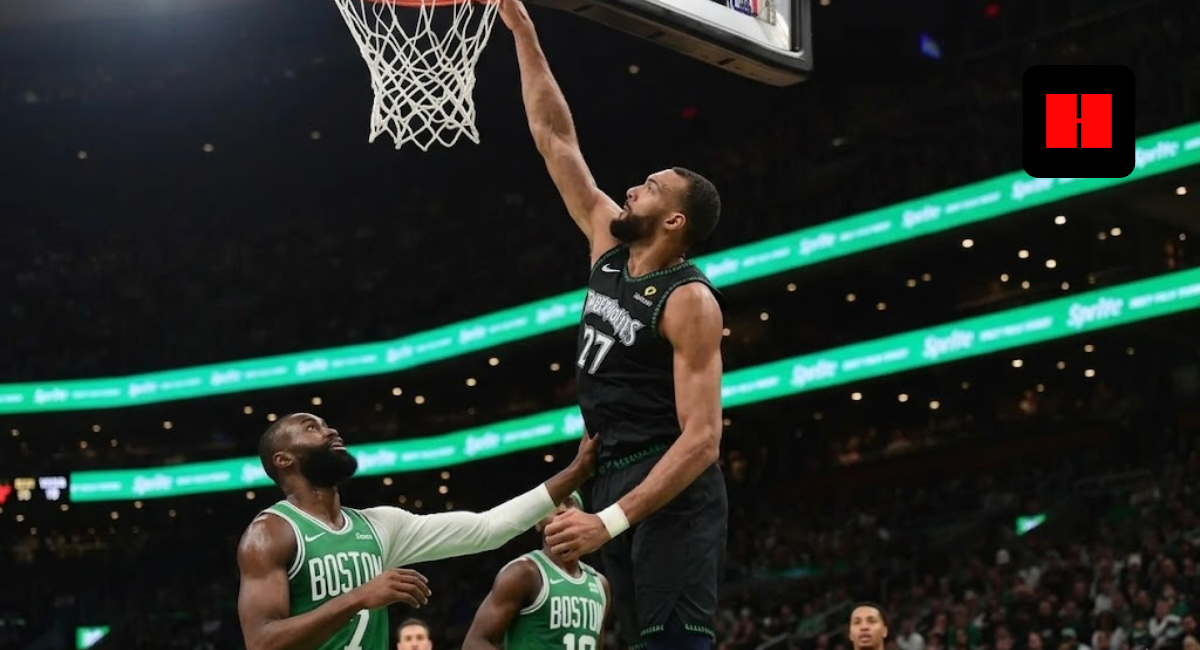 Minnesota Timberwolves center Rudy Gobert #27 reaching for a layup against Jaylen Brown of the Boston Celtics during an NBA game.