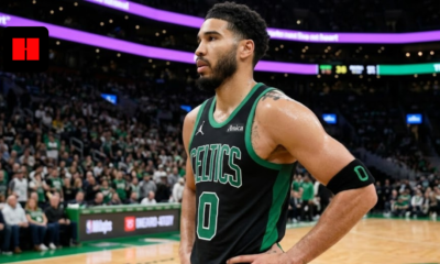 Jayson Tatum standing on the court in a black and green Boston Celtics Statement Edition jersey with hands on hips.