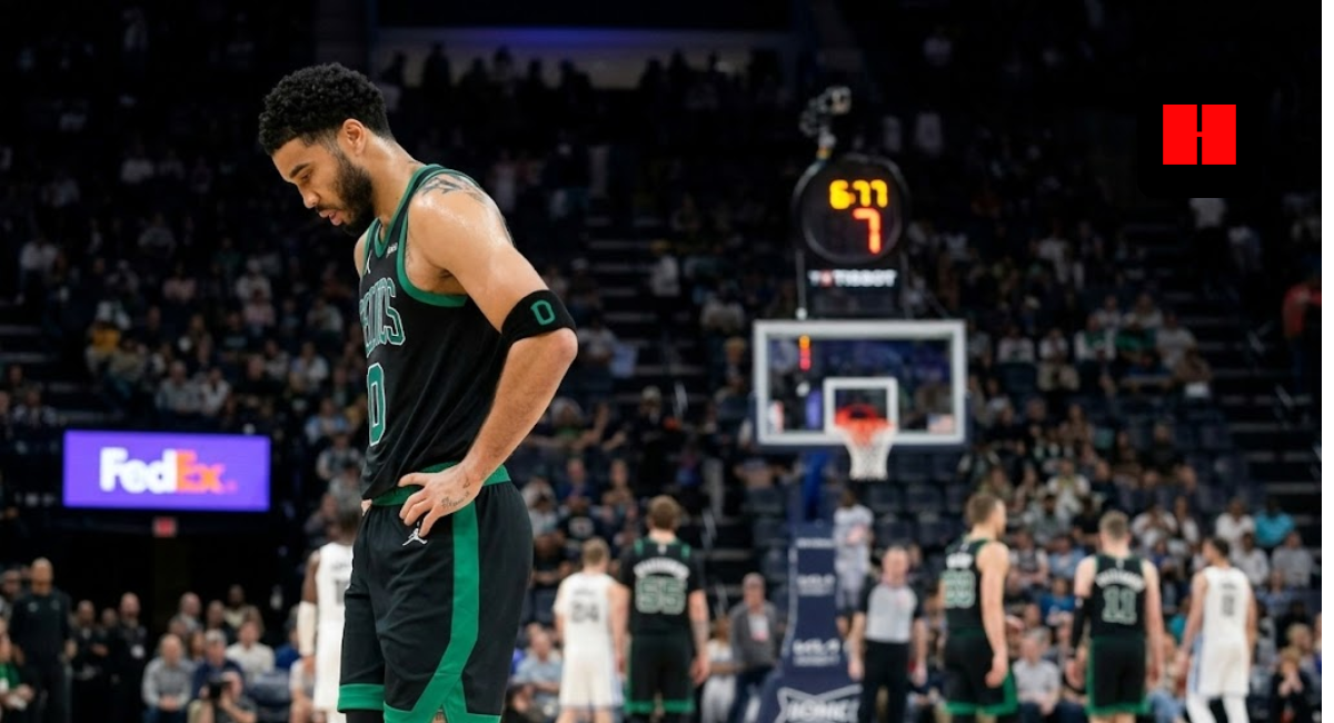 Boston Celtics player Jayson Tatum standing on a basketball court in a black and green jersey, looking down during a game.