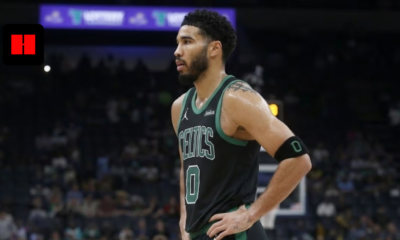 Boston Celtics forward Jayson Tatum in a black and green jersey standing on the basketball court with hands on hips during a game.