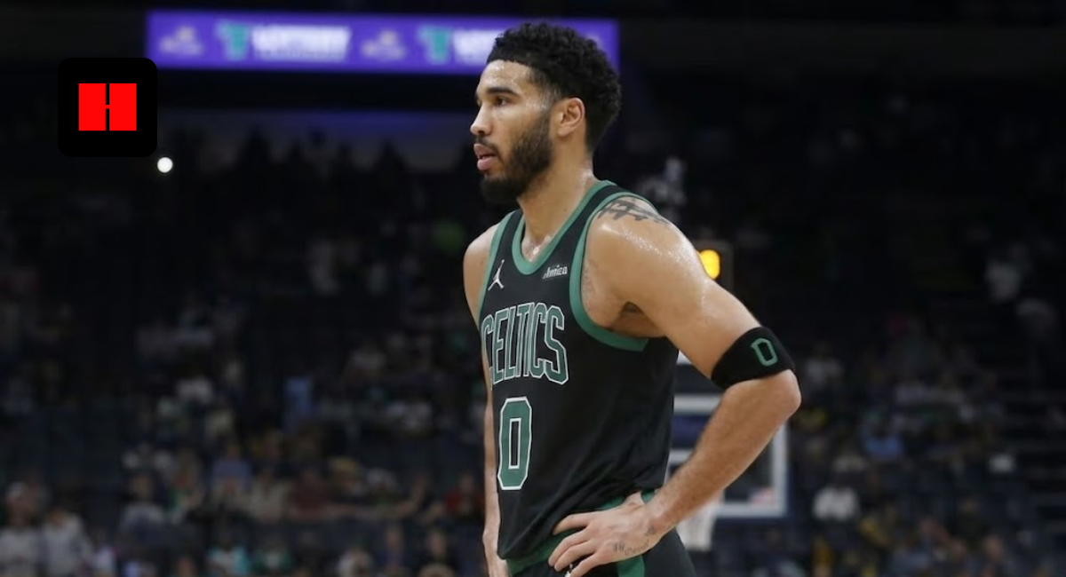 Boston Celtics forward Jayson Tatum in a black and green jersey standing on the basketball court with hands on hips during a game.