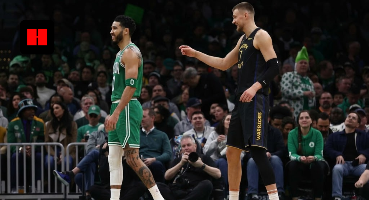 Jayson Tatum in a green Boston Celtics jersey smiling next to Kristaps Porziņģis in a Golden State Warriors jersey during an NBA game.