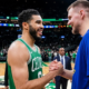 Two tall men, Jayson Tatum and Kristaps Porzingis, in green and blue basketball jerseys respectively, smiling as they shake hands on a crowded basketball court.