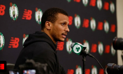 Boston Celtics head coach Joe Mazzulla speaking at a press conference podium with New Balance and team logos in the background.