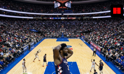 Joel Embiid reacts with hands on head during a late-game moment in a packed Sixers vs Knicks matchup at an indoor NBA arena