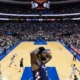 Joel Embiid reacts with hands on head during a late-game moment in a packed Sixers vs Knicks matchup at an indoor NBA arena