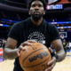 Joel Embiid warming up with a basketball on the Philadelphia 76ers home court before a game, wearing team gear inside the arena in 2026