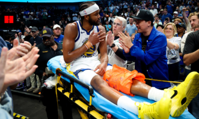 Moses Moody of the Golden State Warriors being helped off the court by trainers after suffering a season-ending knee injury against the Dallas Mavericks.
