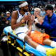 Moses Moody of the Golden State Warriors being helped off the court by trainers after suffering a season-ending knee injury against the Dallas Mavericks.