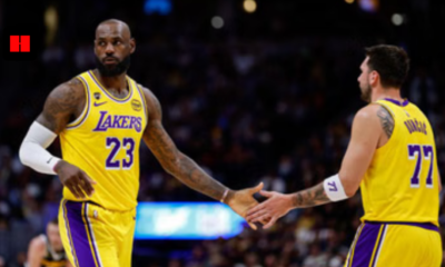 Basketball player in yellow Los Angeles Lakers jersey number 77 signaling with hand during game