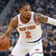 New York Knicks player dribbling past Golden State Warriors defender during NBA game action