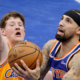 New York Knicks player attempting a layup against Charlotte Hornets defender during an NBA game
