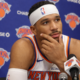 New York Knicks player speaking at a press conference with microphones during NBA media day