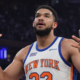New York Knicks player showing emotional reaction with raised hands during live NBA game in arena captured