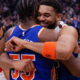 New York Knicks players hugging and celebrating together on the basketball court after the game