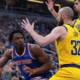 New York Knicks player driving to the basket while Indiana Pacers defenders attempt to block during an NBA game
