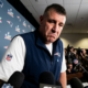 New England Patriots coach speaks to media during Super Bowl press conference with microphones and reporters gathered around