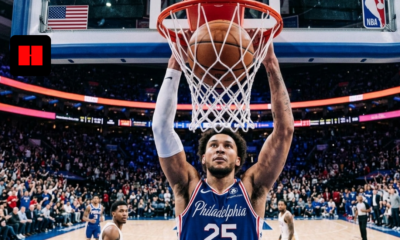 Philadelphia 76ers player finishes a powerful dunk during an NBA game at Xfinity Mobile Arena with the crowd reacting in the background.