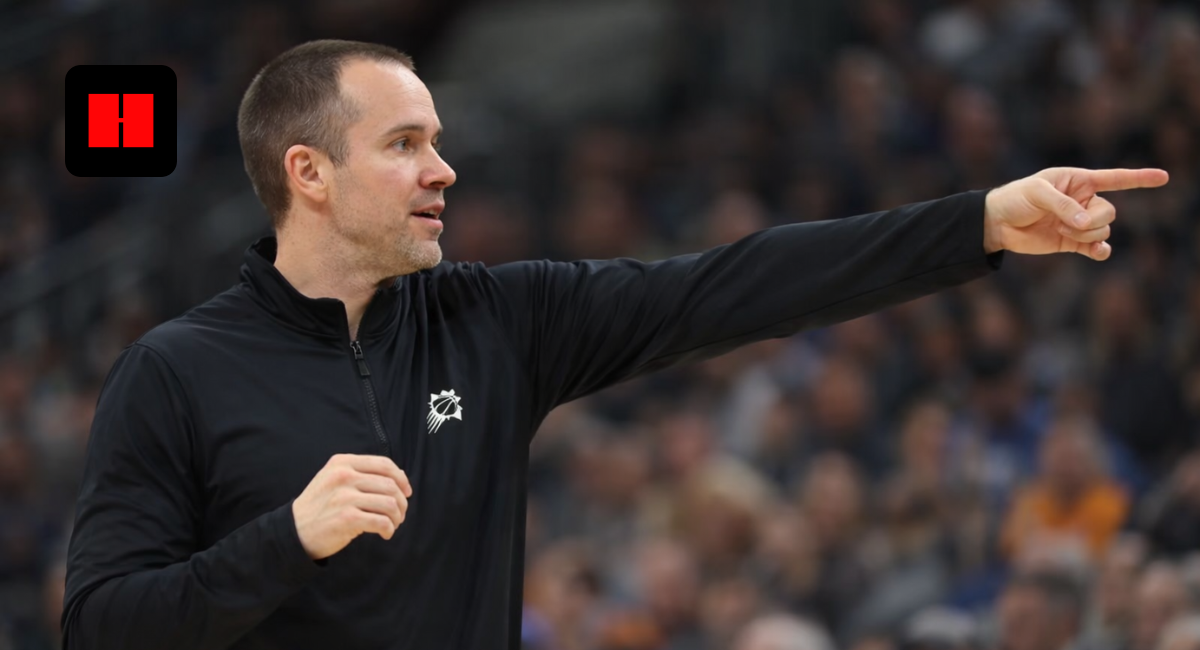 Phoenix Suns head coach pointing and giving instructions from the sideline during an NBA game with crowd in background.