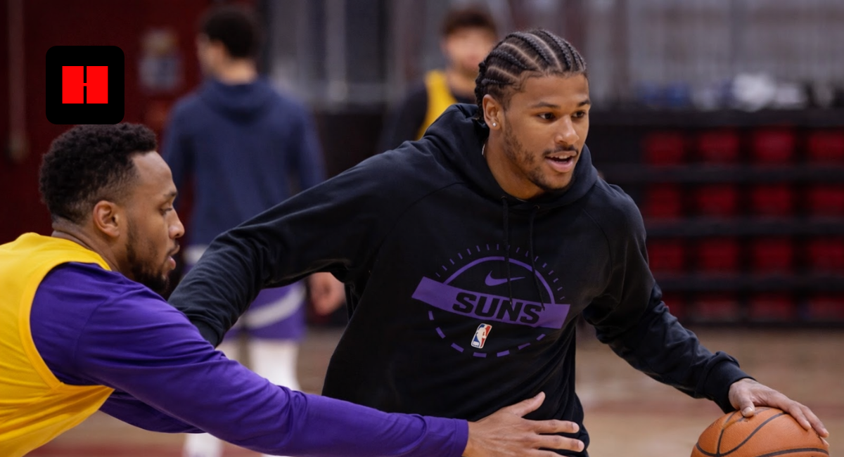 Phoenix Suns player dribbling basketball during indoor practice session with defender in training gym.